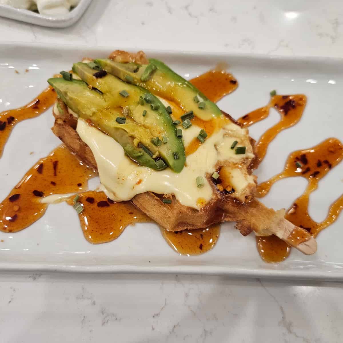 waffle pop with melted cheese, avocado, and hot honey drizzle