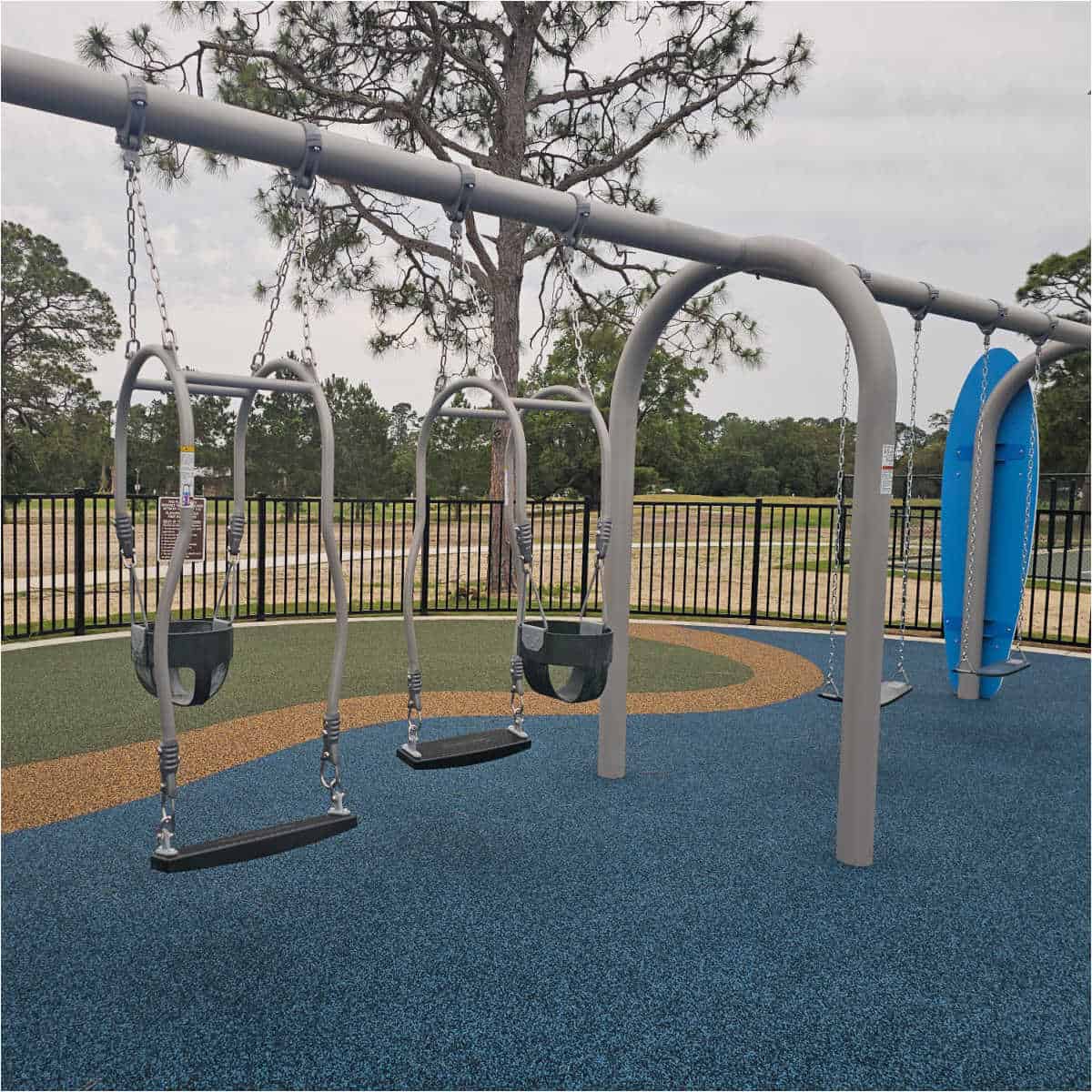 swing set with baby swings and kid swings trees in the background