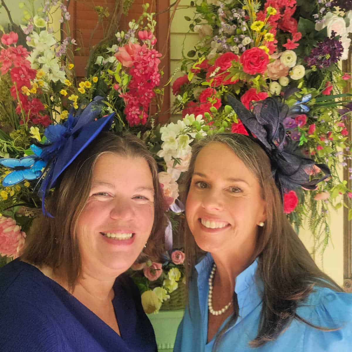 Tammilee and Eva with fancy tea hats on with a floral background