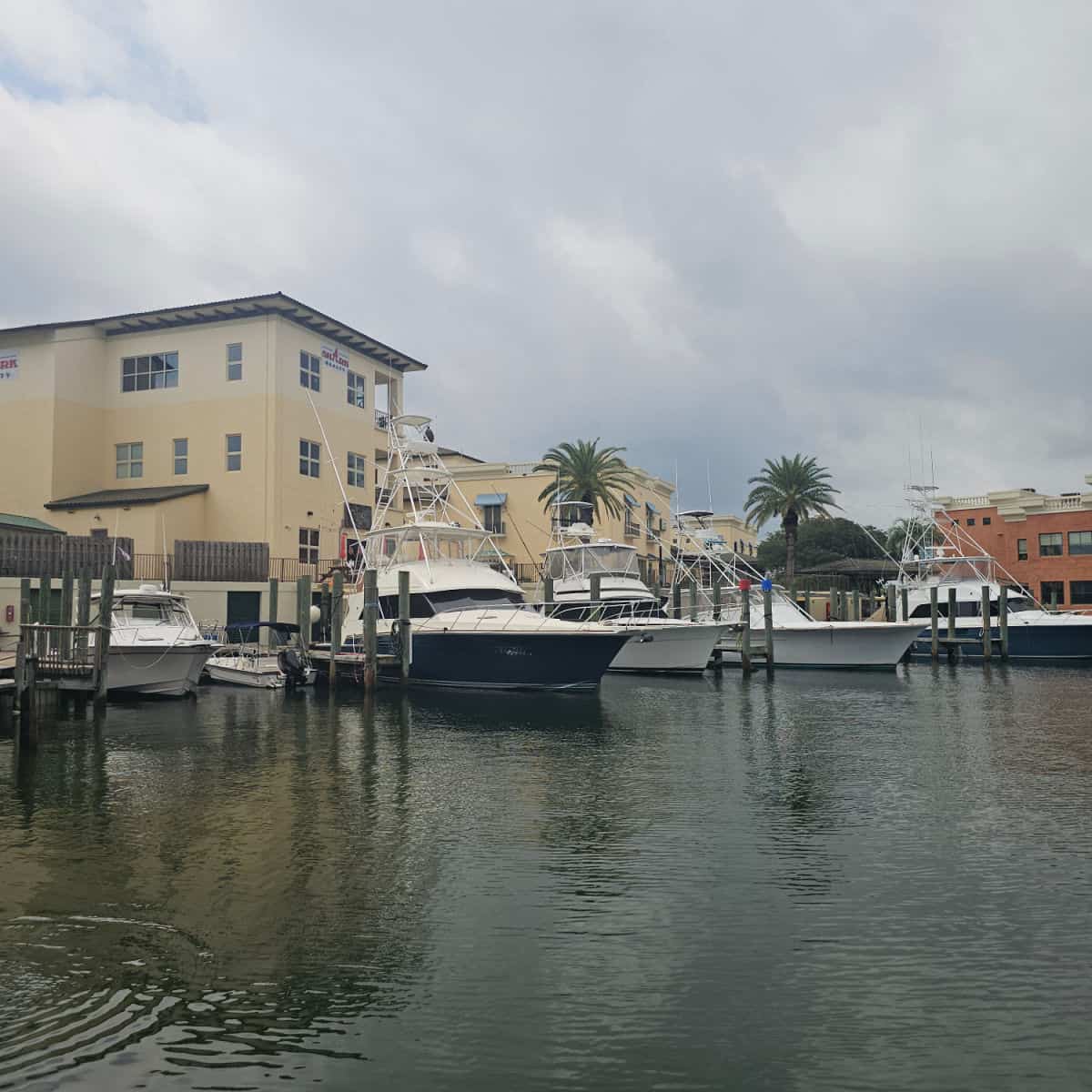 looking over the water to boats docked and tan buildings behind them in Orange Beach