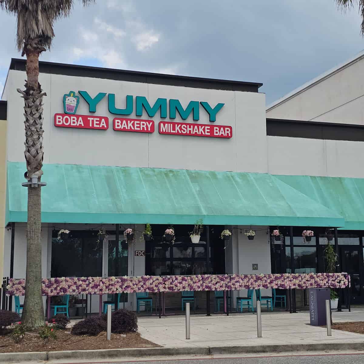 Yummy Boba Tea, Bakery, and Milkshake bar sign over a green awning and outdoor seating