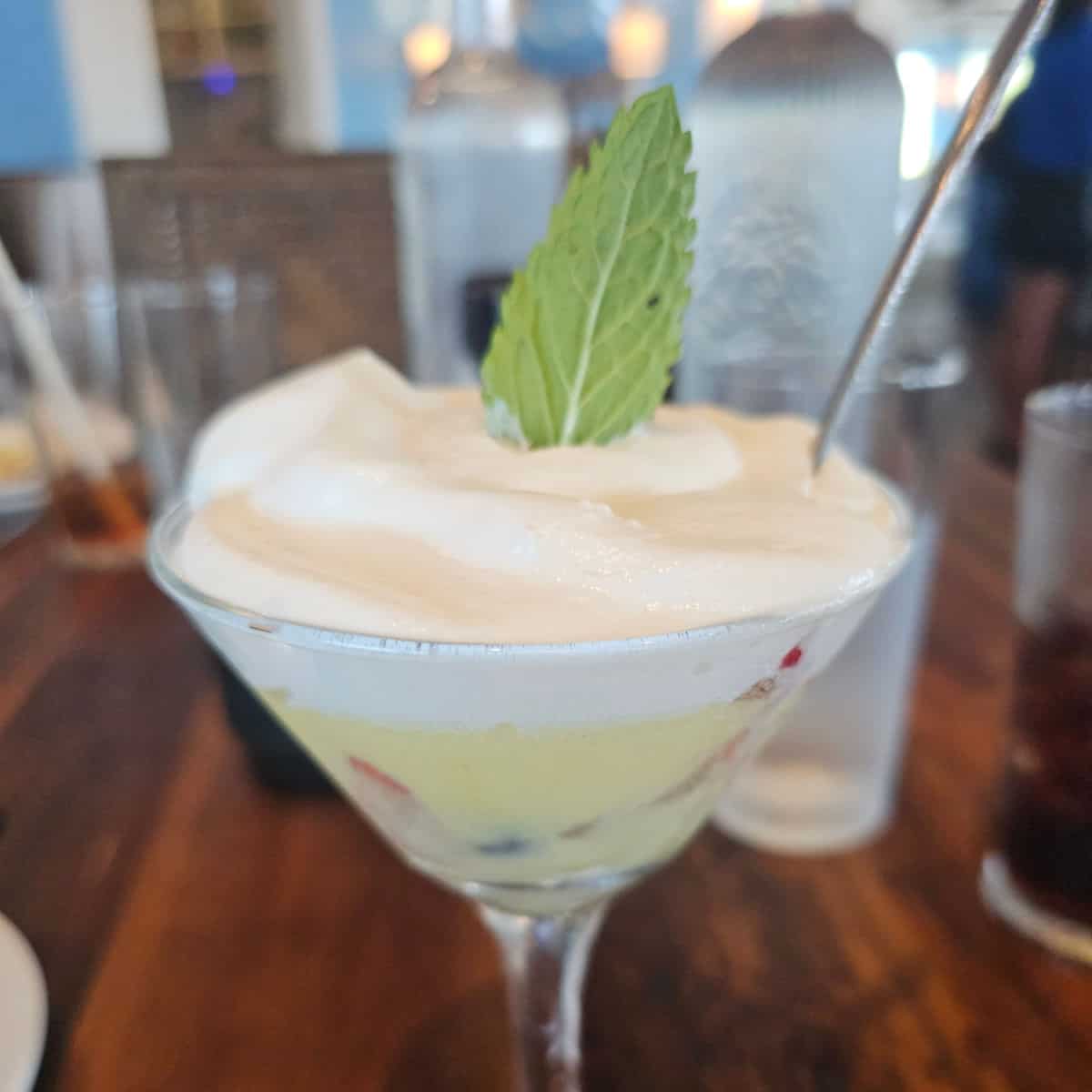 fruit dish covered in cream with a leaf and spoon in the martini glass