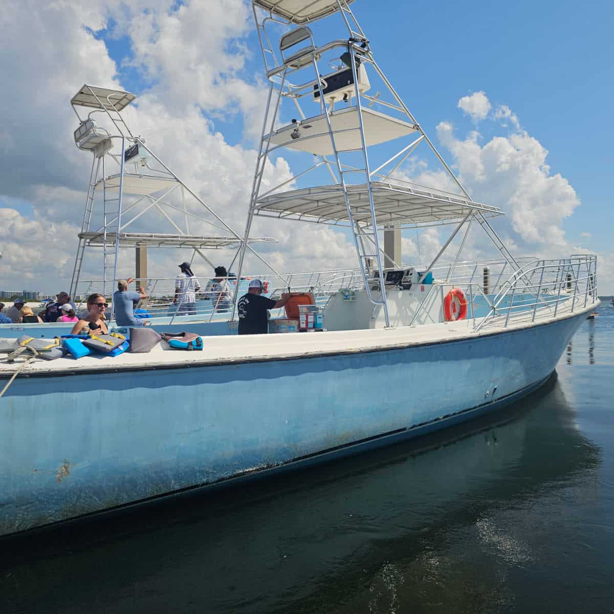 Blue and white boat with captains chair above the boat next to a 2nd boat