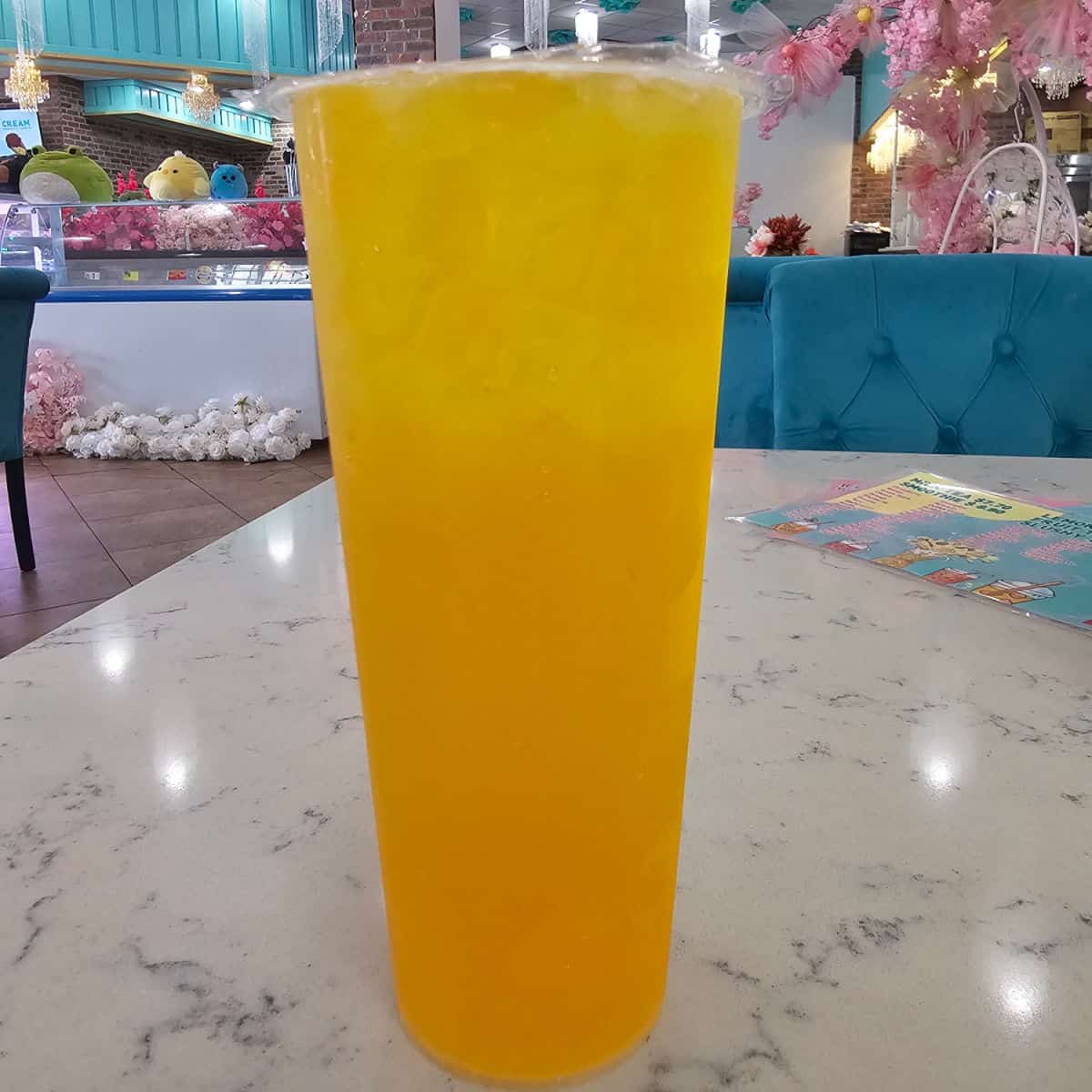 mango boba tea on a table with blue chairs and flowers behind it