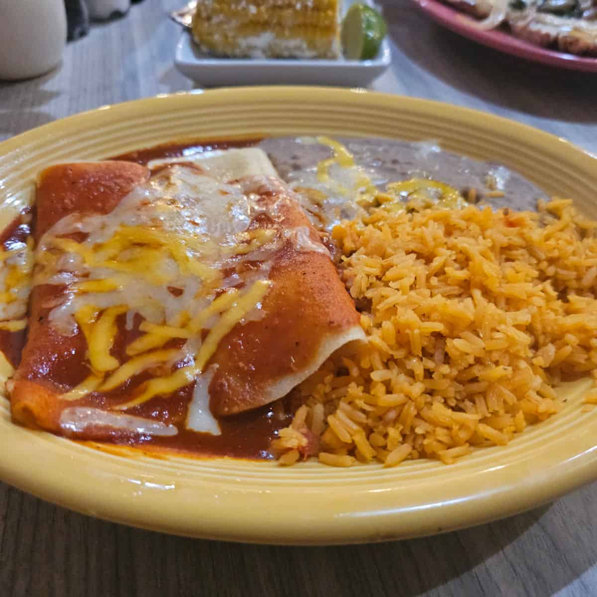 enchiladas with rice and beans aon a yellow plate