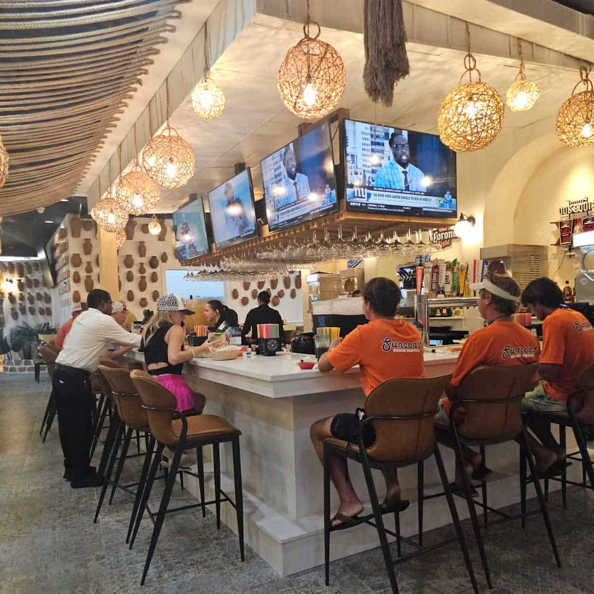 indoor bar with tvs over the bar, tall bar seats and lights all the way around the bar