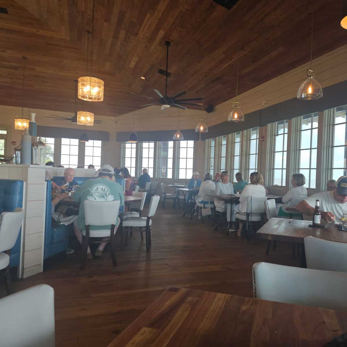 Jesse's on the Bay indoor seating with tables and chairs wrapped around the room, large windows looking out towards the water