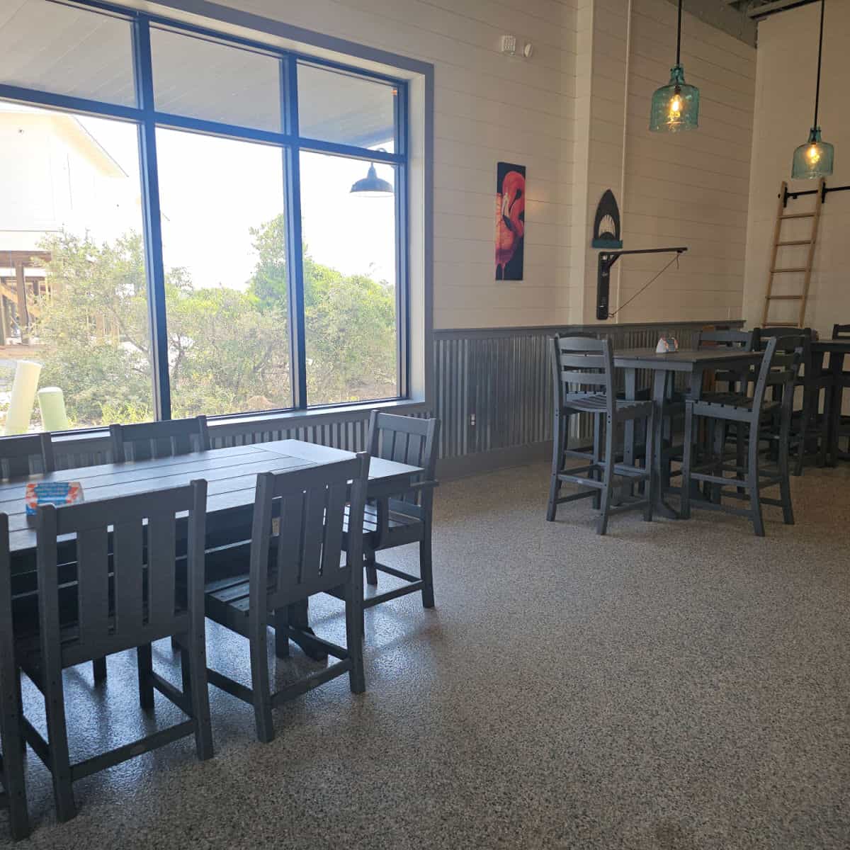 Indoor seating with a low and tall table with windows along the far wall