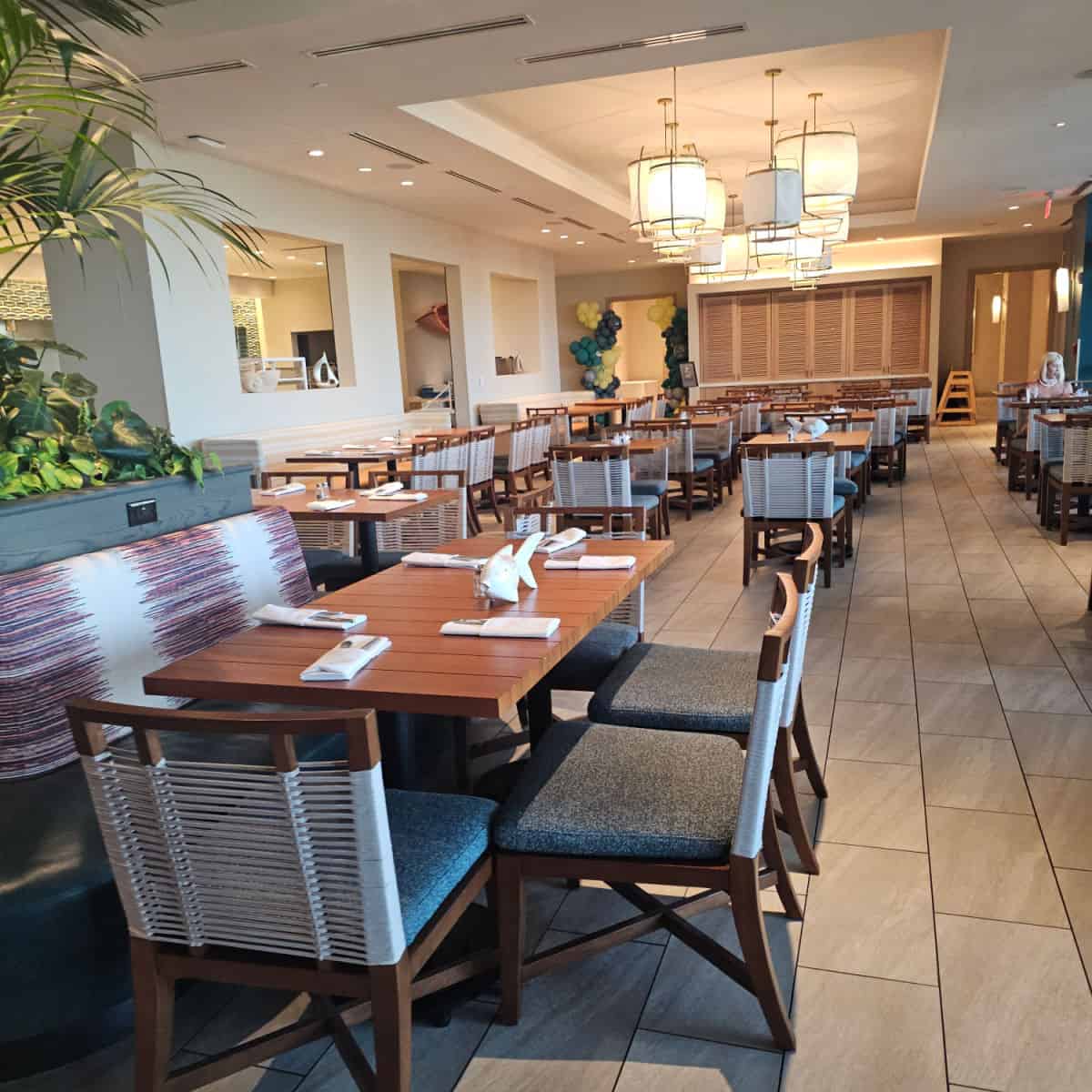 indoor seating with rows of tables and chairs, greenery on the left, balloon display at the back of the room
