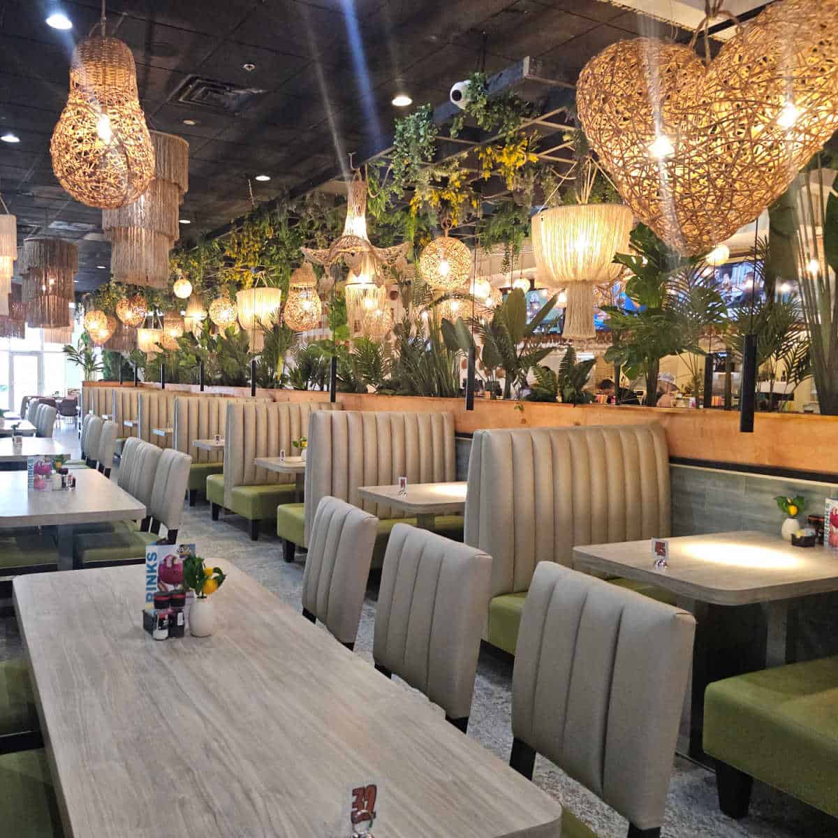 indoor seating with tables and chairs, lights hanging from the ceiling with greenery.