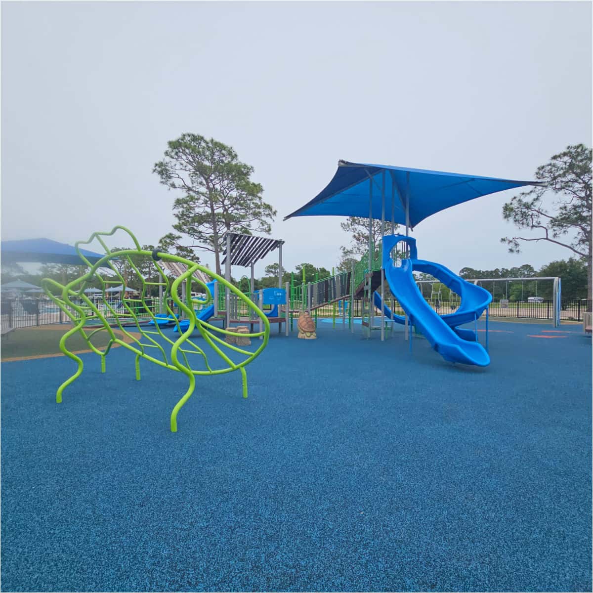 kids playground with blue slides and cover, green fish to climb on
