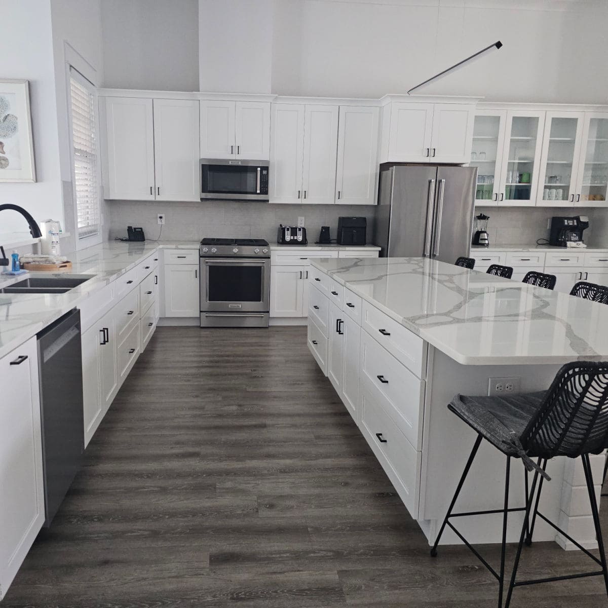 Large kitchen with white cabinets, stainless steel appliances, white island with counters