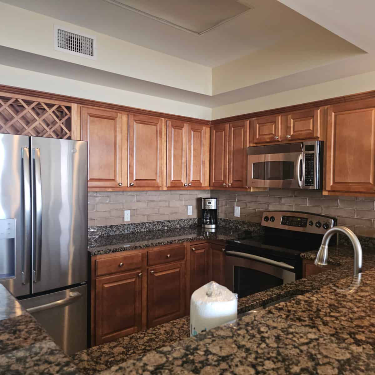 kitchen with wood cabinets, granite countertops and stainless steel appliances with a coffee maker on the counter