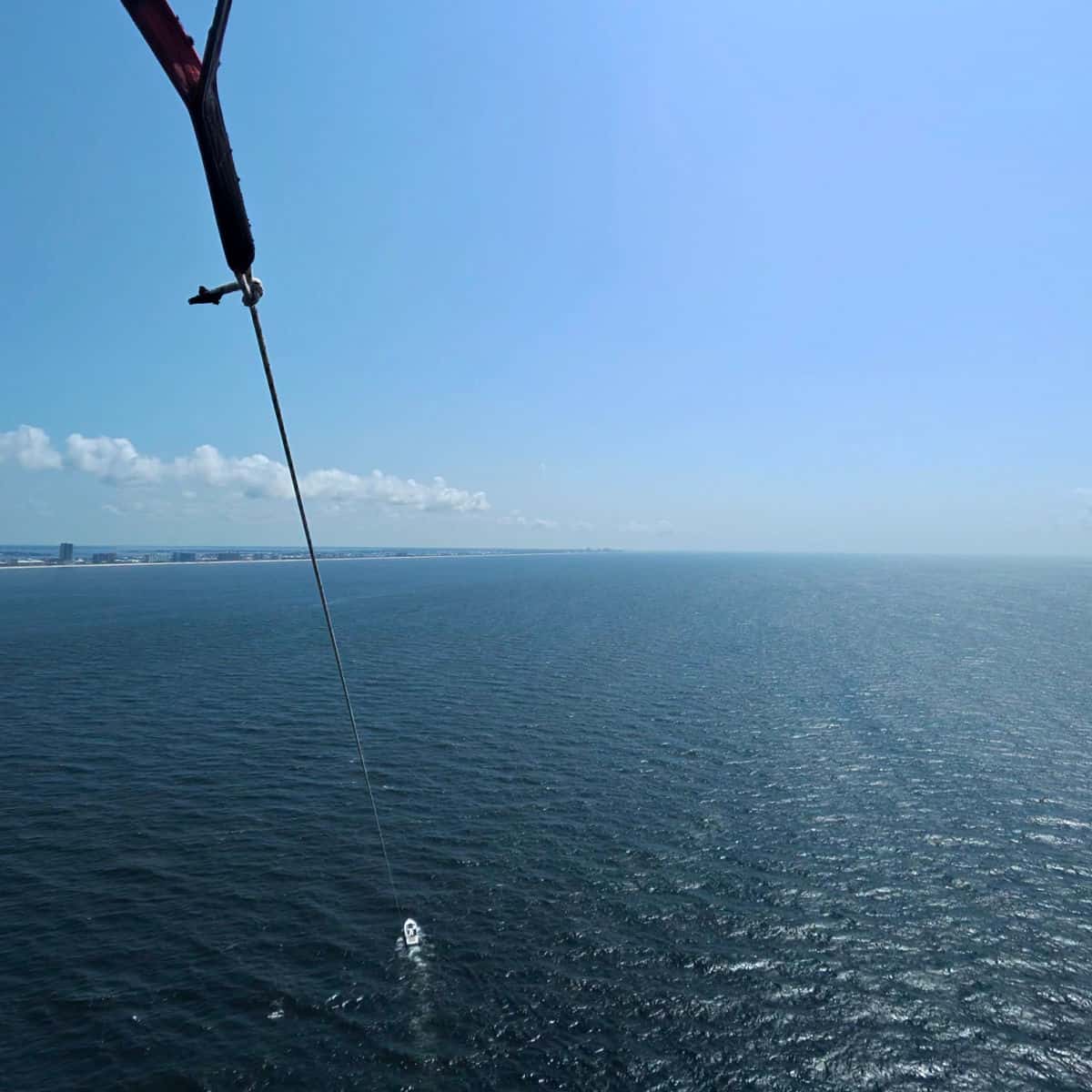 Looking down a really long rope to a boat in the Gulf while parasailing