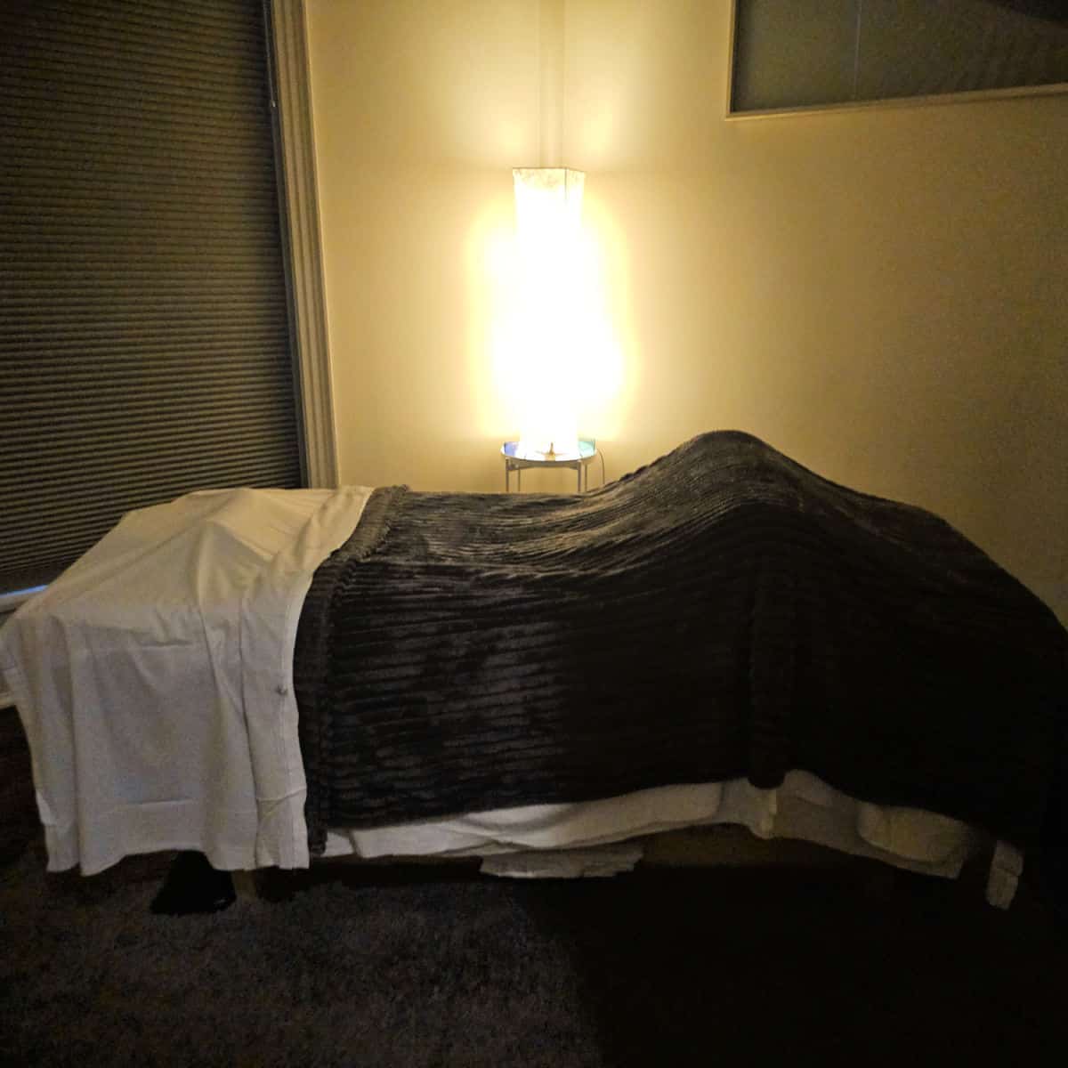massage bed with light behind it, blankets over the bed