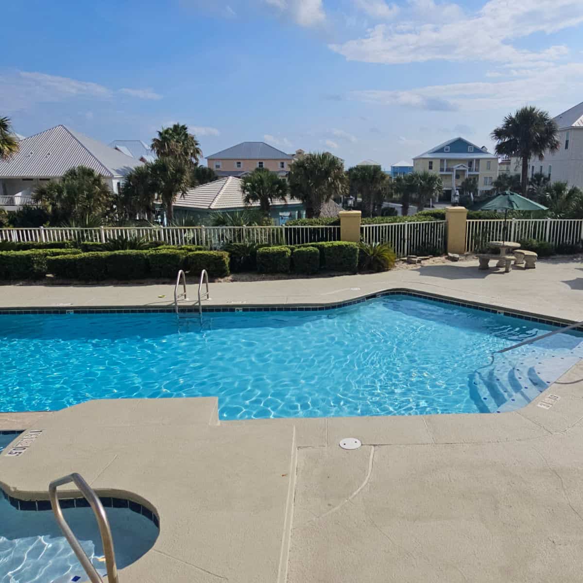 outdoor pool with a concrete table and umbrella on the pool deck
