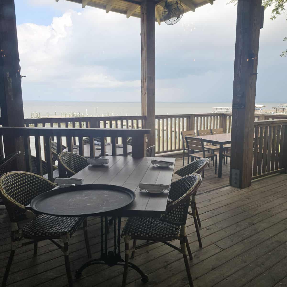 outdoor seating with tables and chairs on the deck looking out over the water