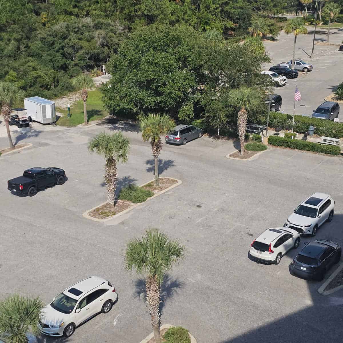 Looking down on the parking lot with a few cars and palm trees in the parking lot