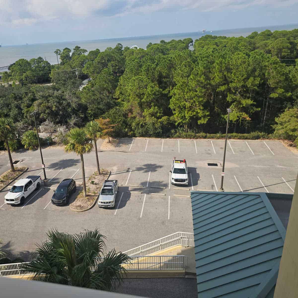 looking over a parking lot with trucks parked towards trees and Mobile Bay