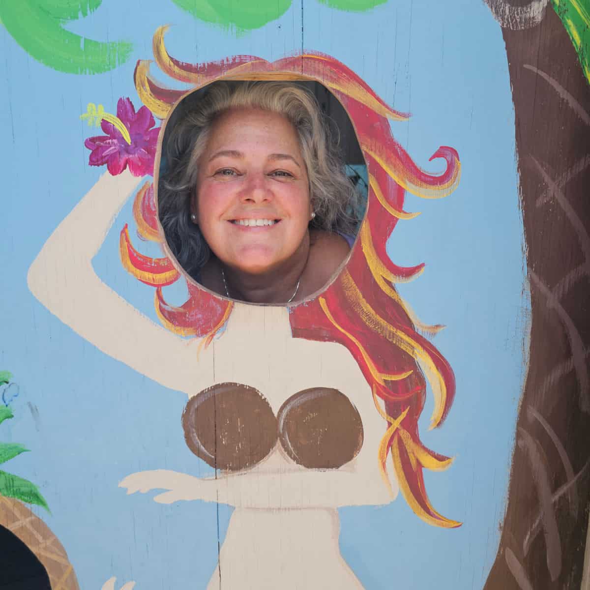 Brandy looking through a cut-out with a bikini girl painted on it