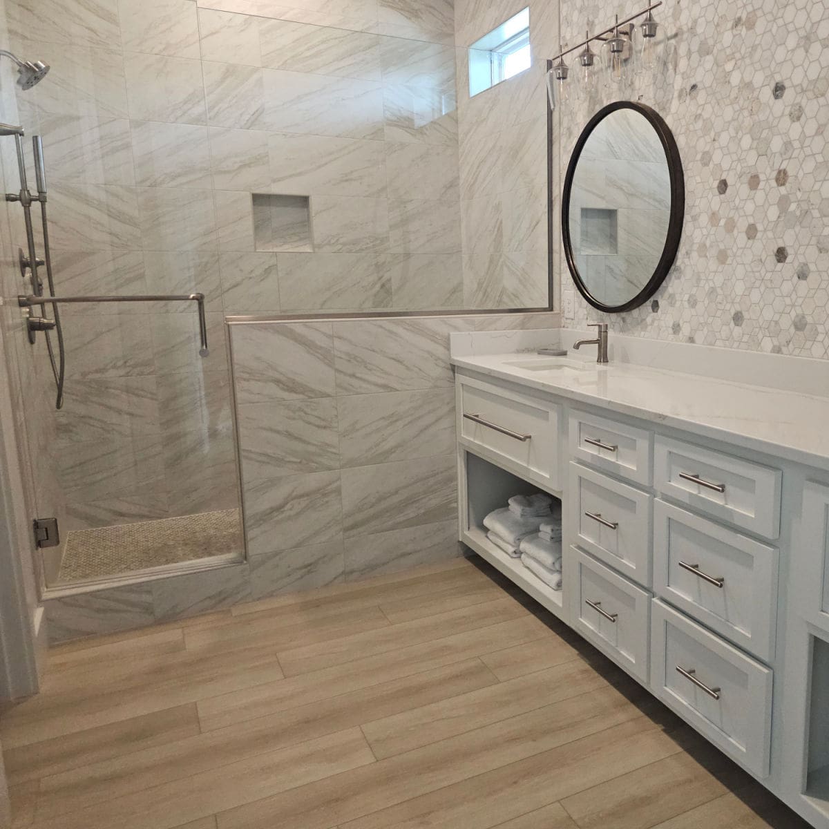 Large primary bathroom with walk in shower, vanity with white cabinets and counter, mirror and gorgeous hexagon tile on the wall