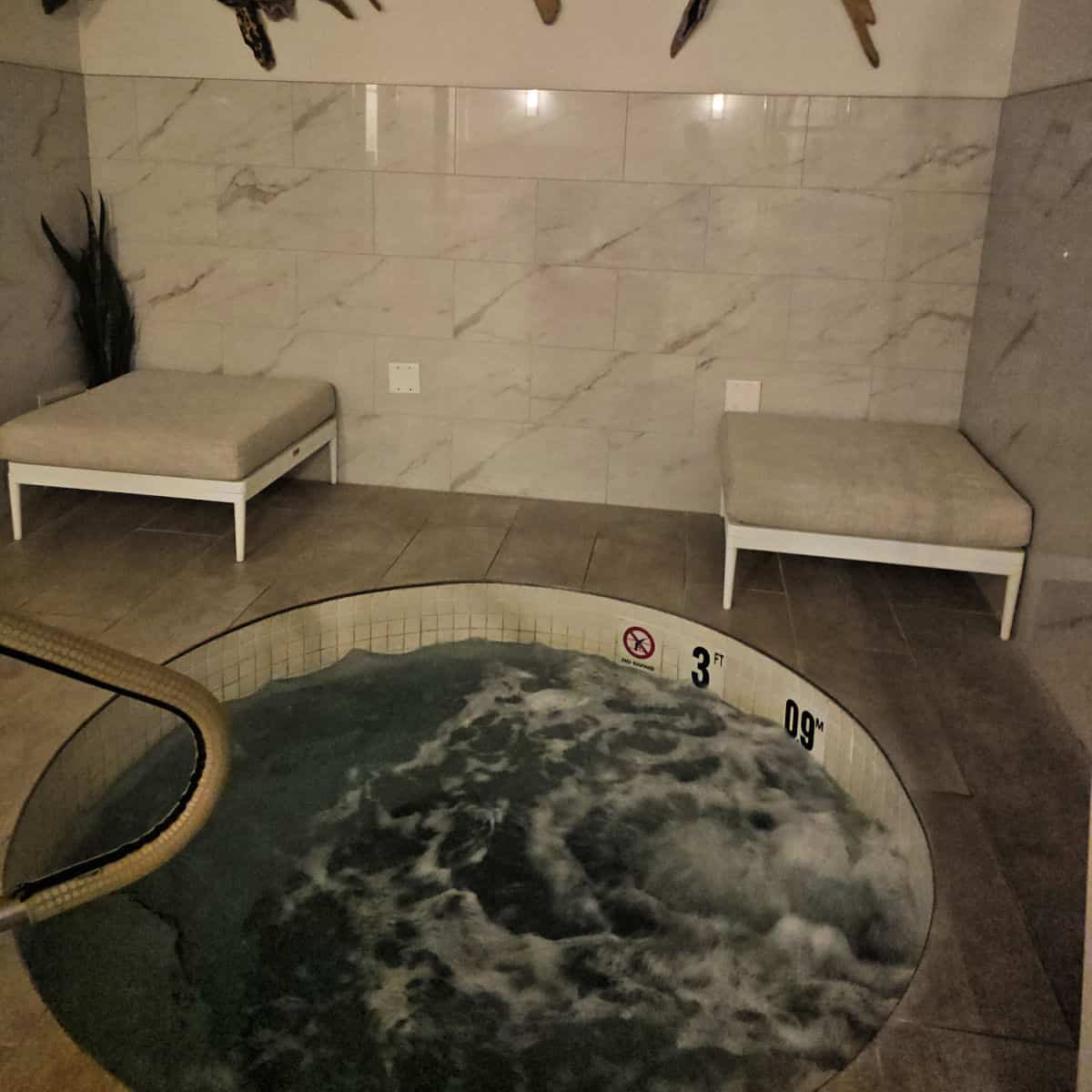 relaxation room with a hot tub and two padded chairs