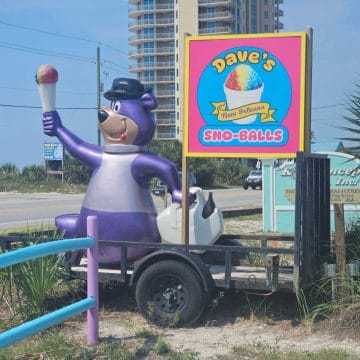 Dave's New Orleans Sno-Balls sign next to a purple bear statue holding a sno-ball