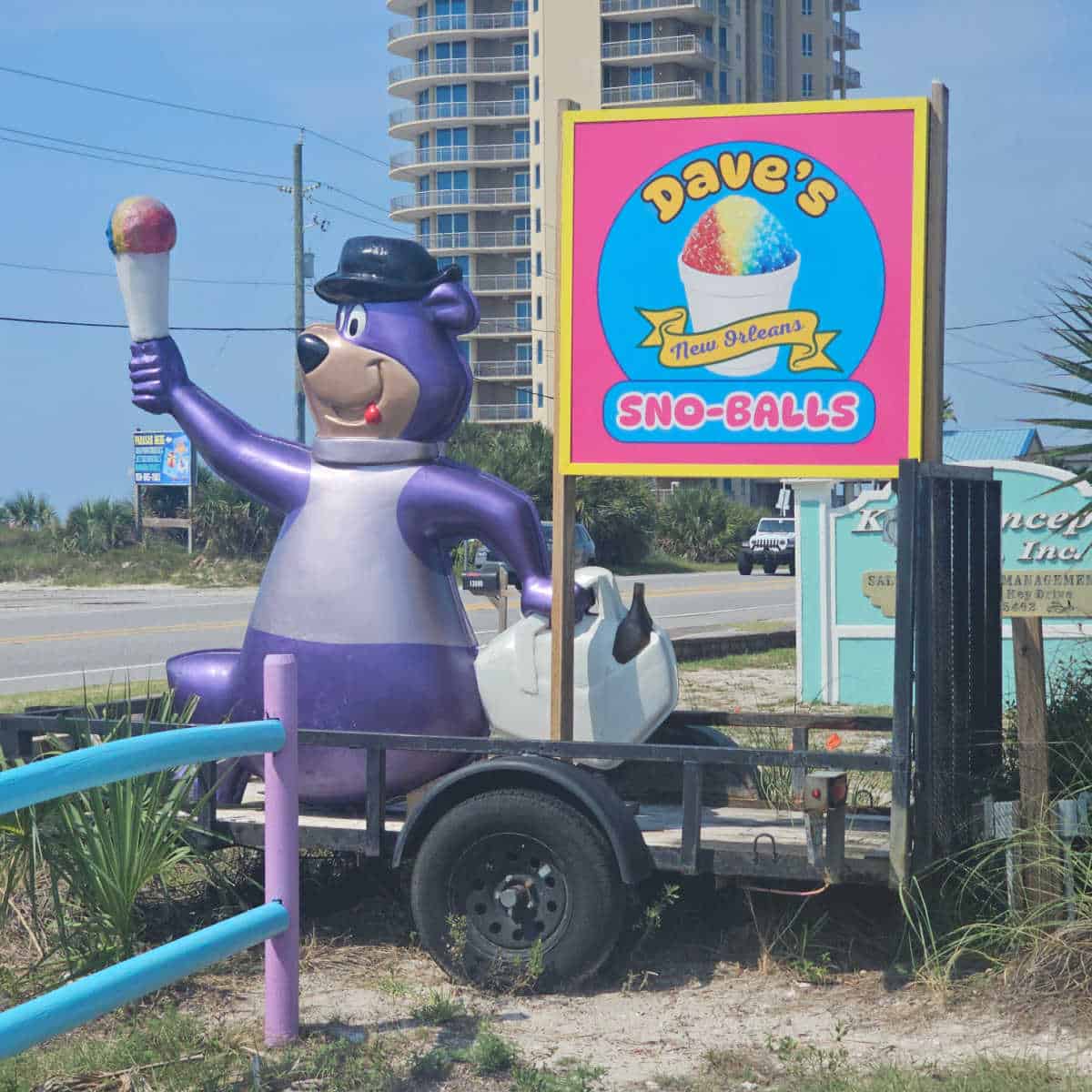 Dave's New Orleans Sno-Balls sign next to a purple bear statue holding a sno-ball