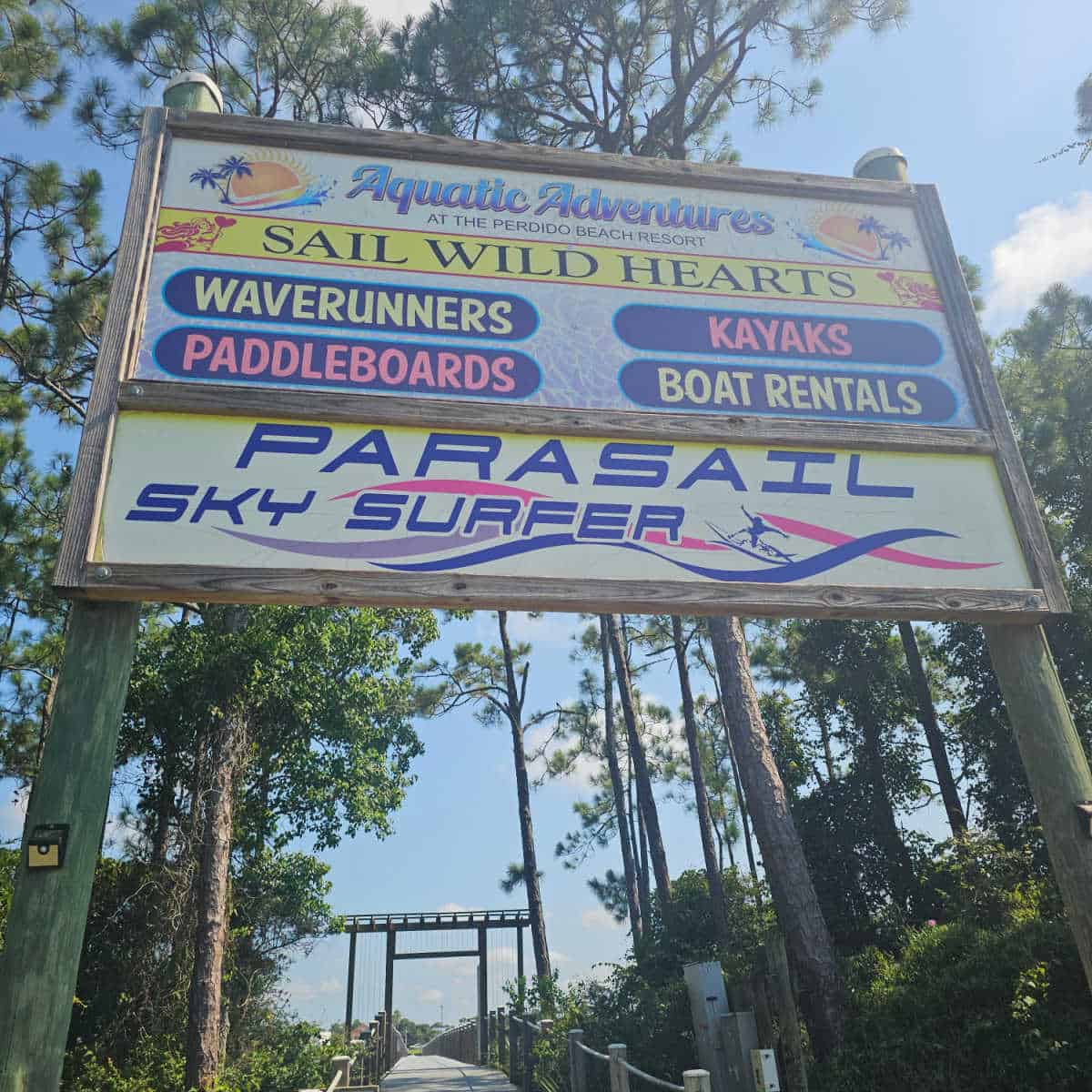 Sail Wild Hearts and Parasail Sky Surfer wooden sign and down leading to the water