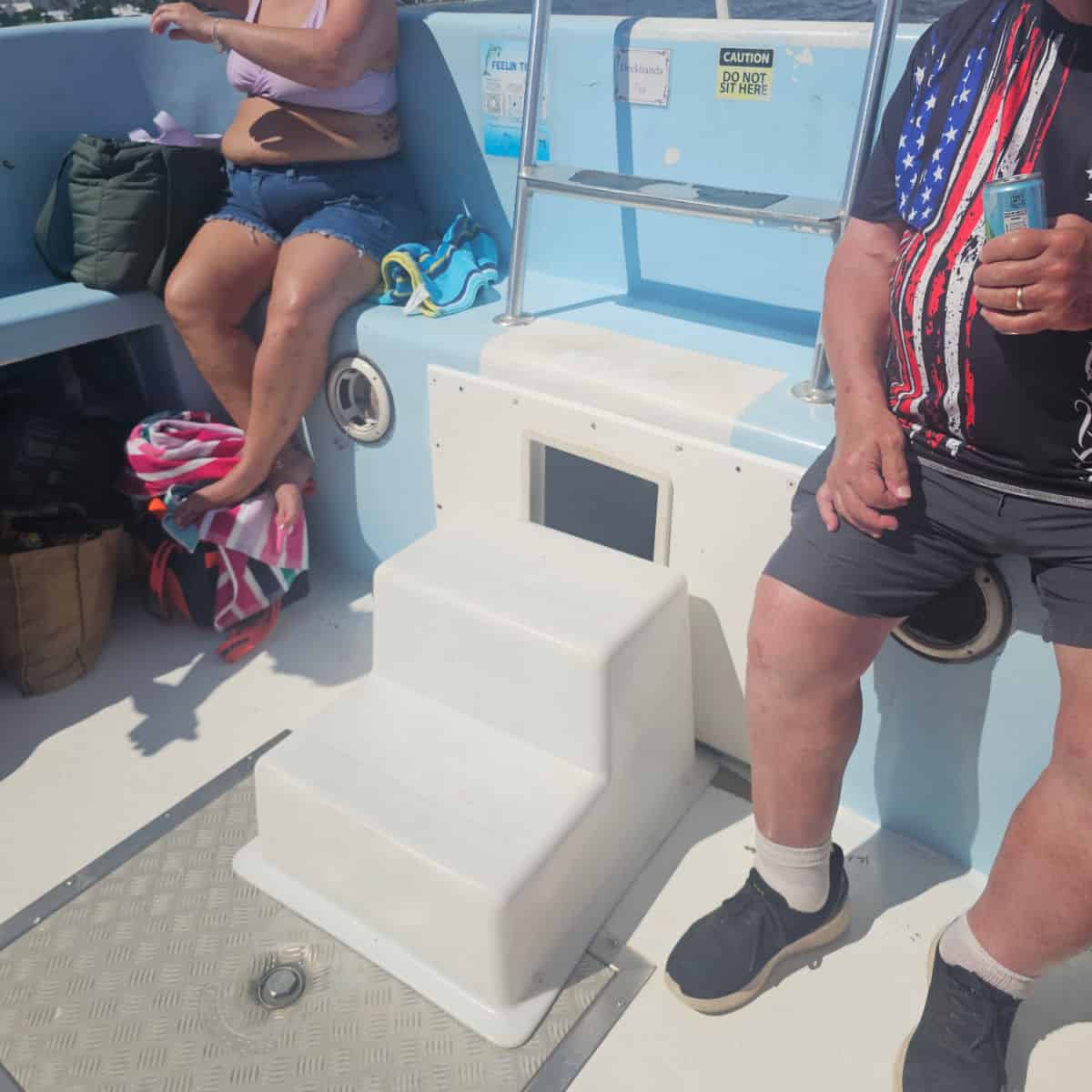 white steps and a ladder to get off the boat. two people sitting next to the ladder