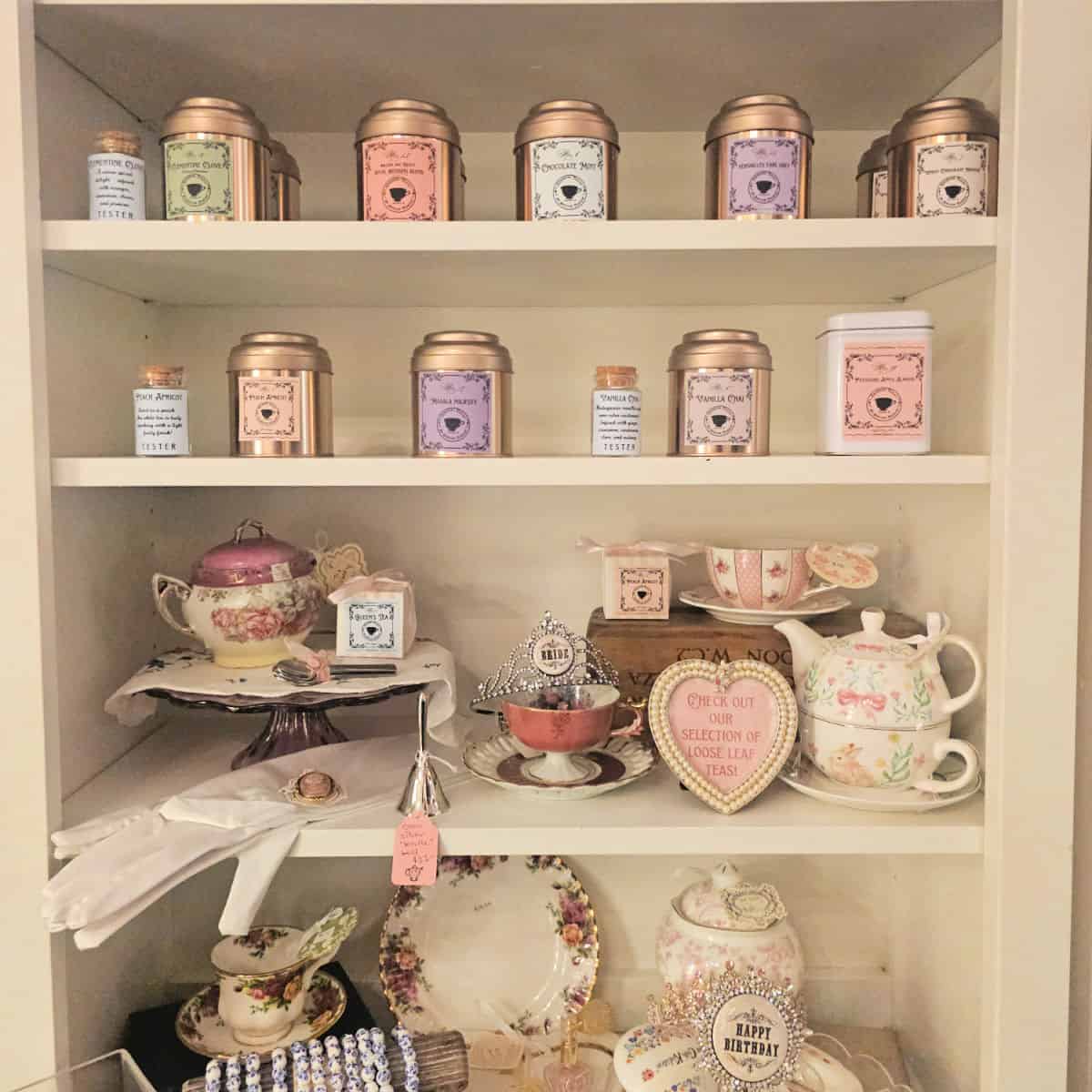 Shelf with containers of tea and tea cups and tea pots